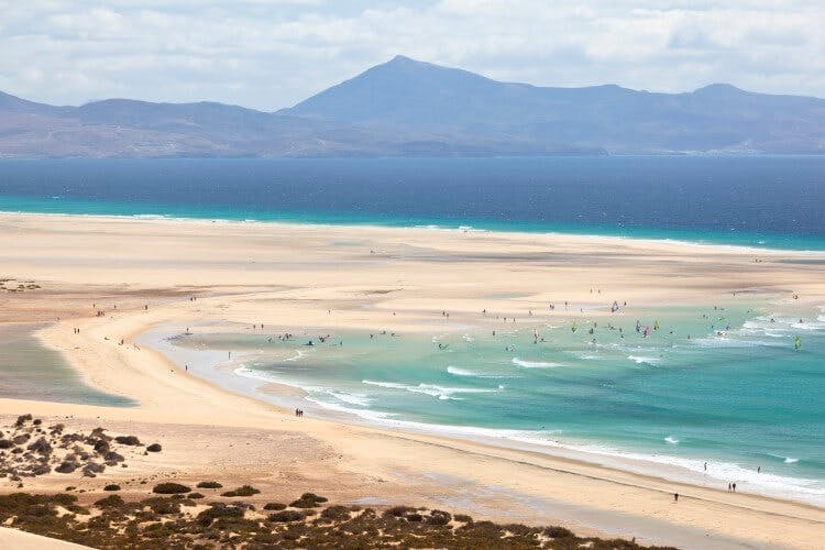 Fuerteventura beach scene with white sand and mountains in the background