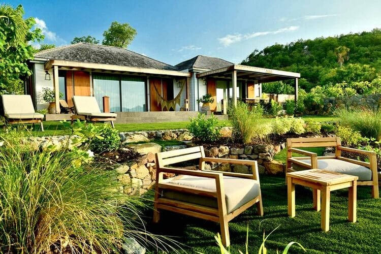 villa with outdoor chairs surrounded by greenery
