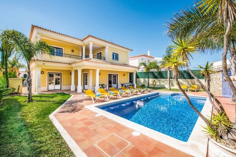 yellow villa with white pillars and pool
