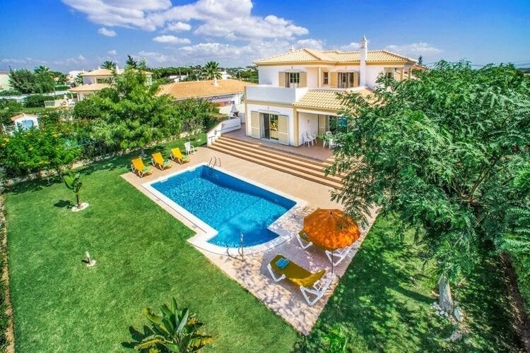 aerial shot of white and yellow villa with lawn and pool