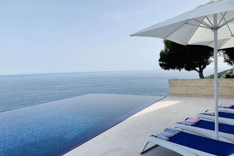infinity pool with loungers and ocean in background