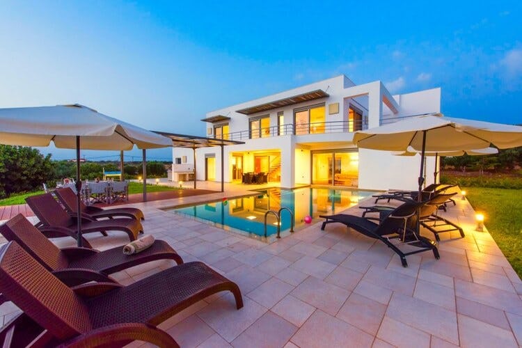 white villa with pool and loungers at dusk