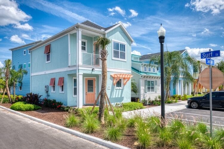 Margaritaville 45 pet-friendly rental - a pale blue villa with pink doors and window shades, and decorative shrubbery in the front garden