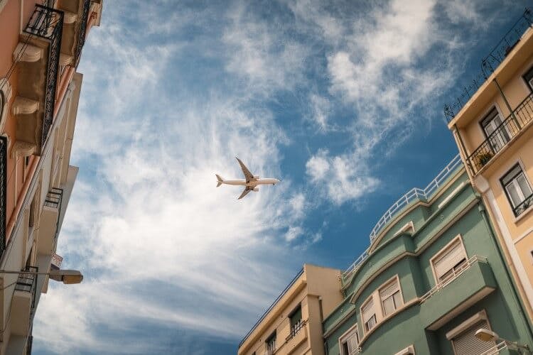 A plane flying over Portuguese buildings