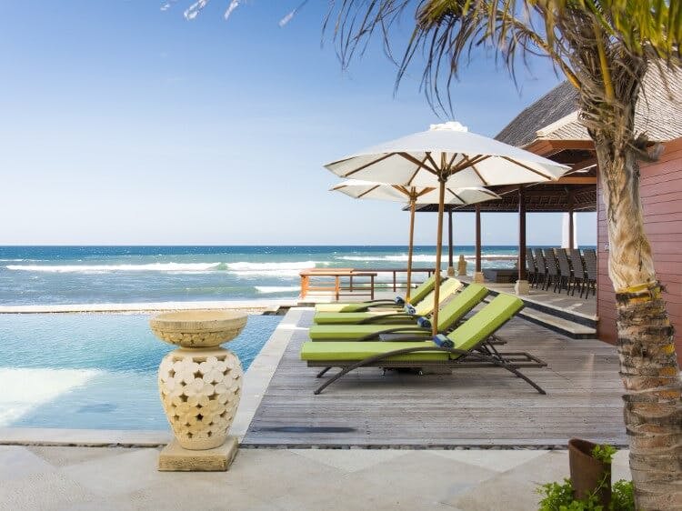 loungers and pool with ocean in background