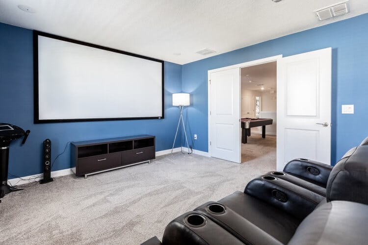 a blue home movie theater with black leather chairs