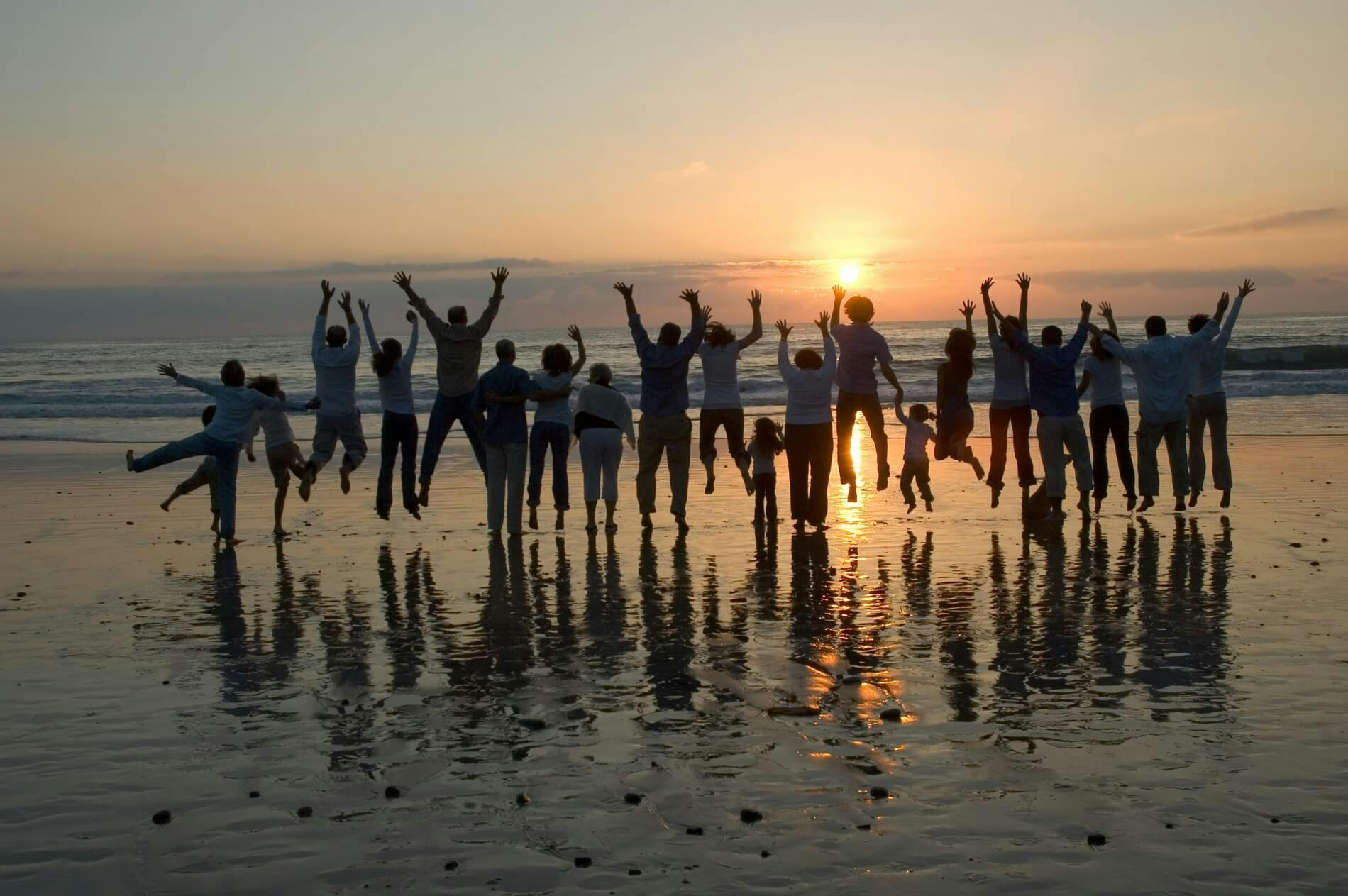 large group of people on a beach at sunset