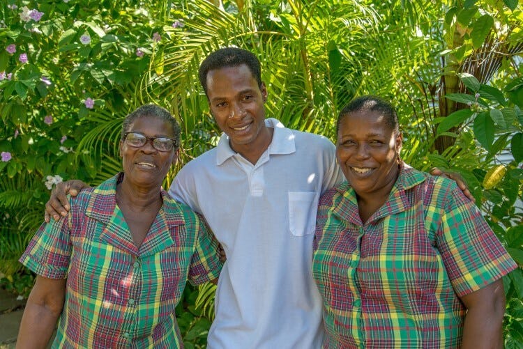 Three members of staff from a Jamaican villa smile for the camera