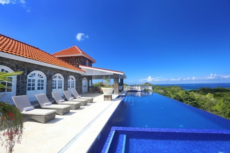 villa with red roof and loungers with infinity pool