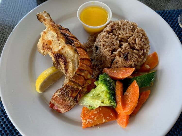 A plate of traditional Caribbean food - lobster, rice, beans and vegetables