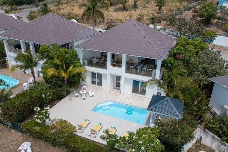 aerial view of white villa with dark roof and pool