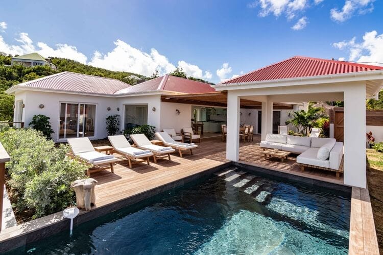 white villa with red roof, seating areas and swimming pool