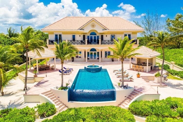 grand manor with palm trees and glass fronted pool