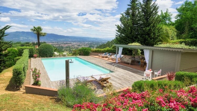 pool on patio overlooking countryside with pink flowers in foreground