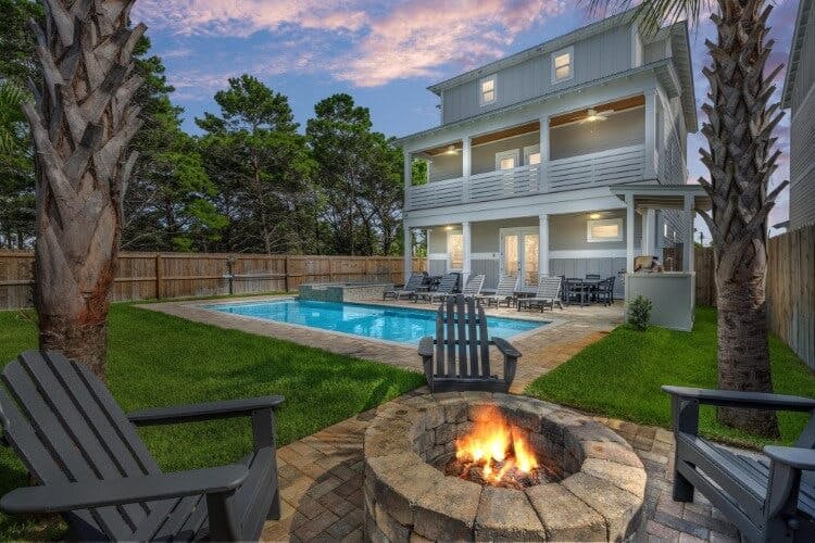 tall vacation rental at dusk with pool and firepit