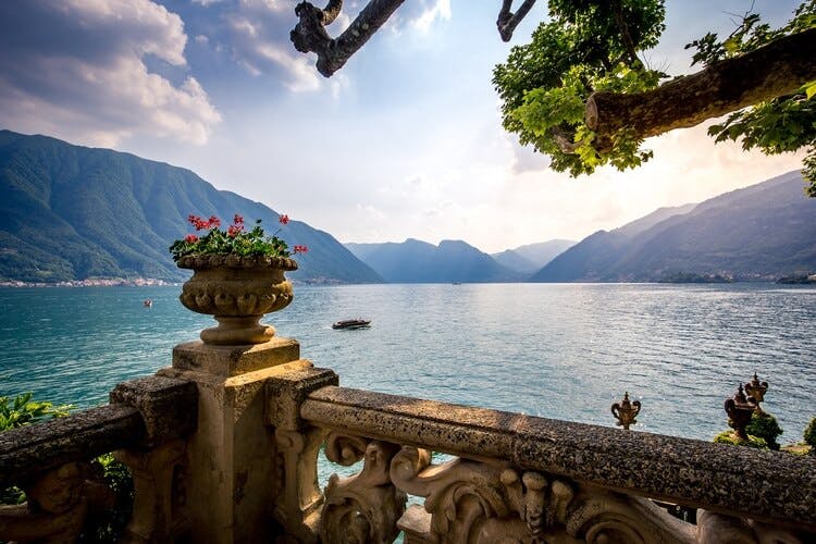The lake of lake como with mountains and a pot of flowers