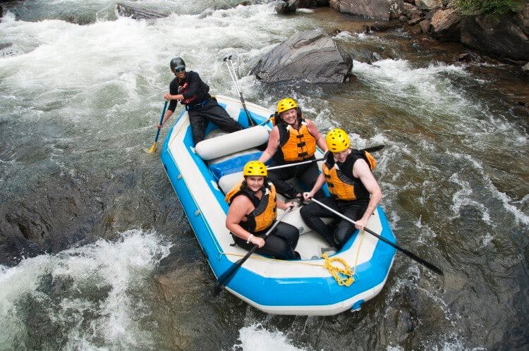 An inflatable boat with 4 people in rushing through white water