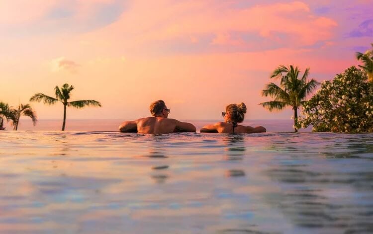 couple relaxing in infinity pool at sunset