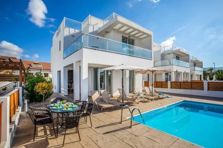 white villa with balcony, dining set and pool