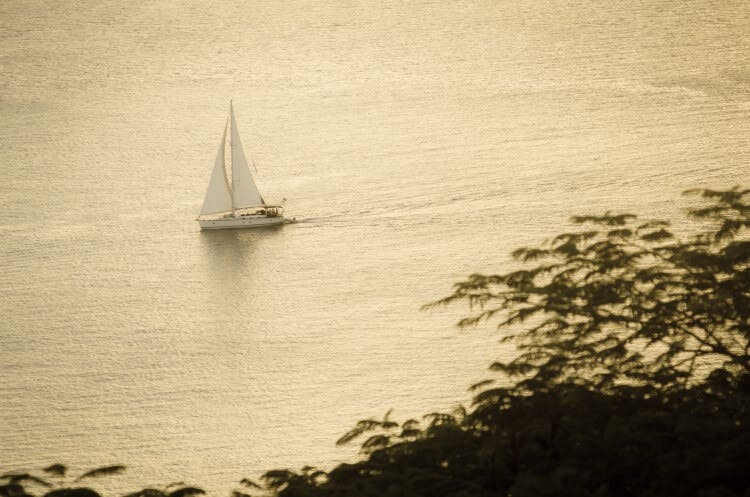 A white sailboat sailing on a flat sea in the Caribbean