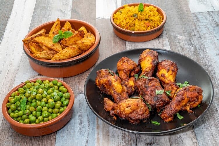 Piri piri chicken with peas and potato wedges served in terracota bowls