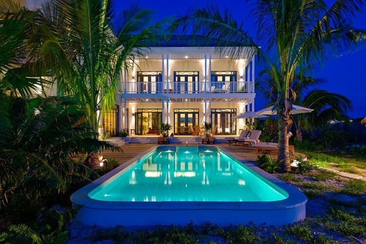 white villa and lit up pool at dusk