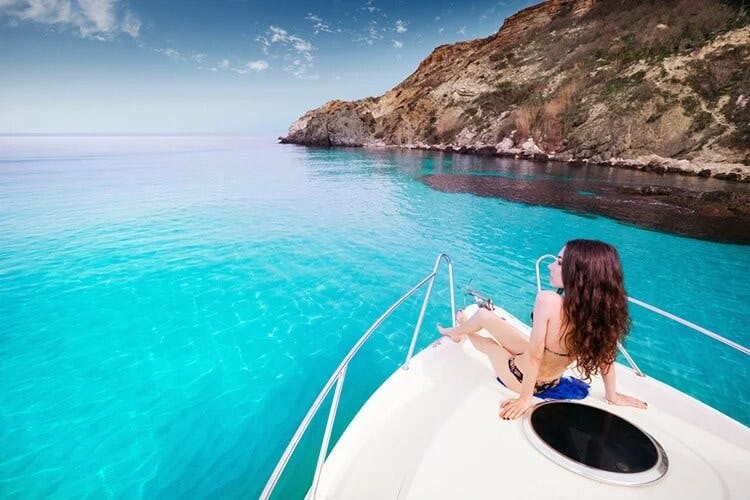woman relaxing on yacht surrounded by water and cliffs