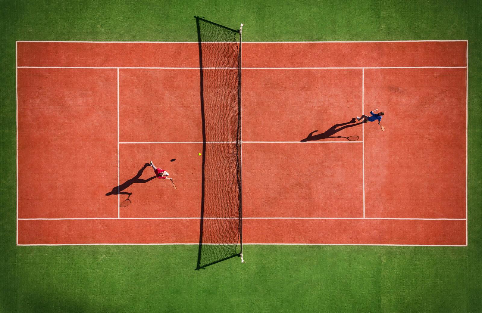 Ariel view of two people playing tennis on a ground covered course