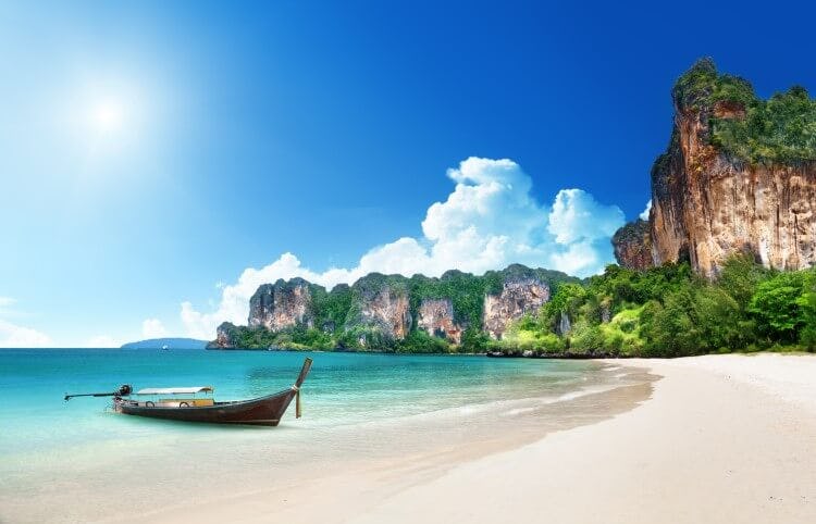 A traditional fishing boat on white sand beach in Krabi, Thailand