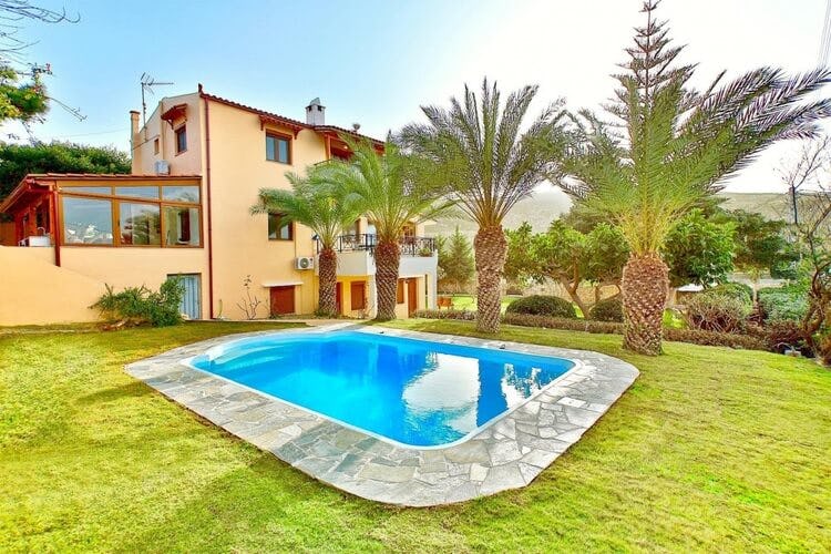 tan and orange villa with pool in lawn and palm trees