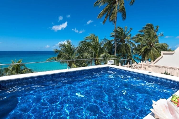 pool on balcony overlooking ocean and palm trees