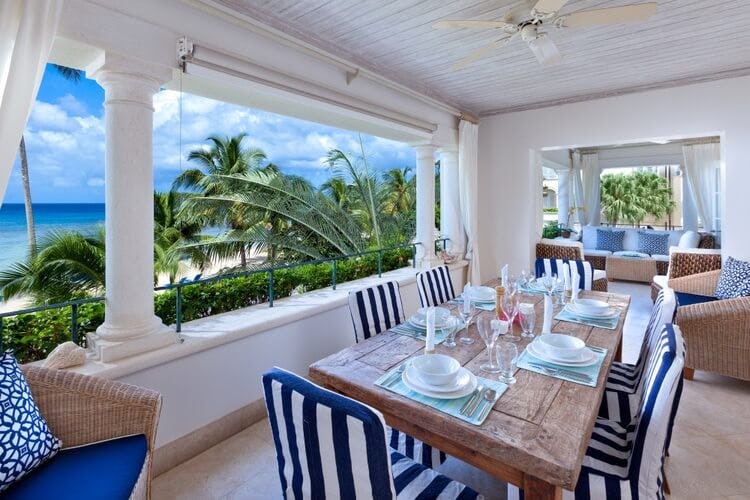blue and white striped dining set on balcony overlooking beach