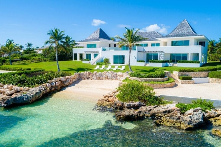 white villa on the beach with rocks and palm trees