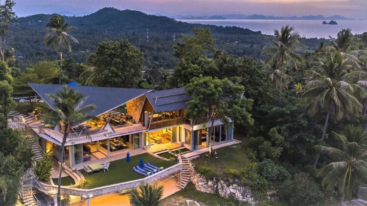 villa at dusk surrounded by trees with ocean in background