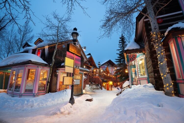 Main Street in Breckenridge during the winter, with thick snow on the pathway and wooden buildings covered in Christmas lights
