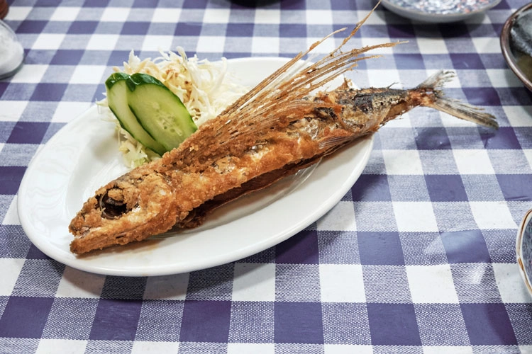 Fried flying fish with salad on a checked tablecloth
