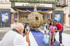 A family gets their photo taken in front of Cinderella's Golden Carriage parked outside a movie theater