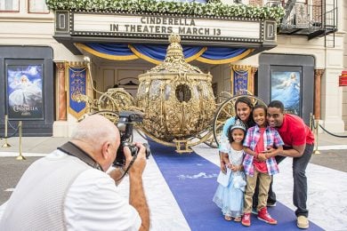 A family gets their photo taken in front of Cinderella's Golden Carriage parked outside a movie theater