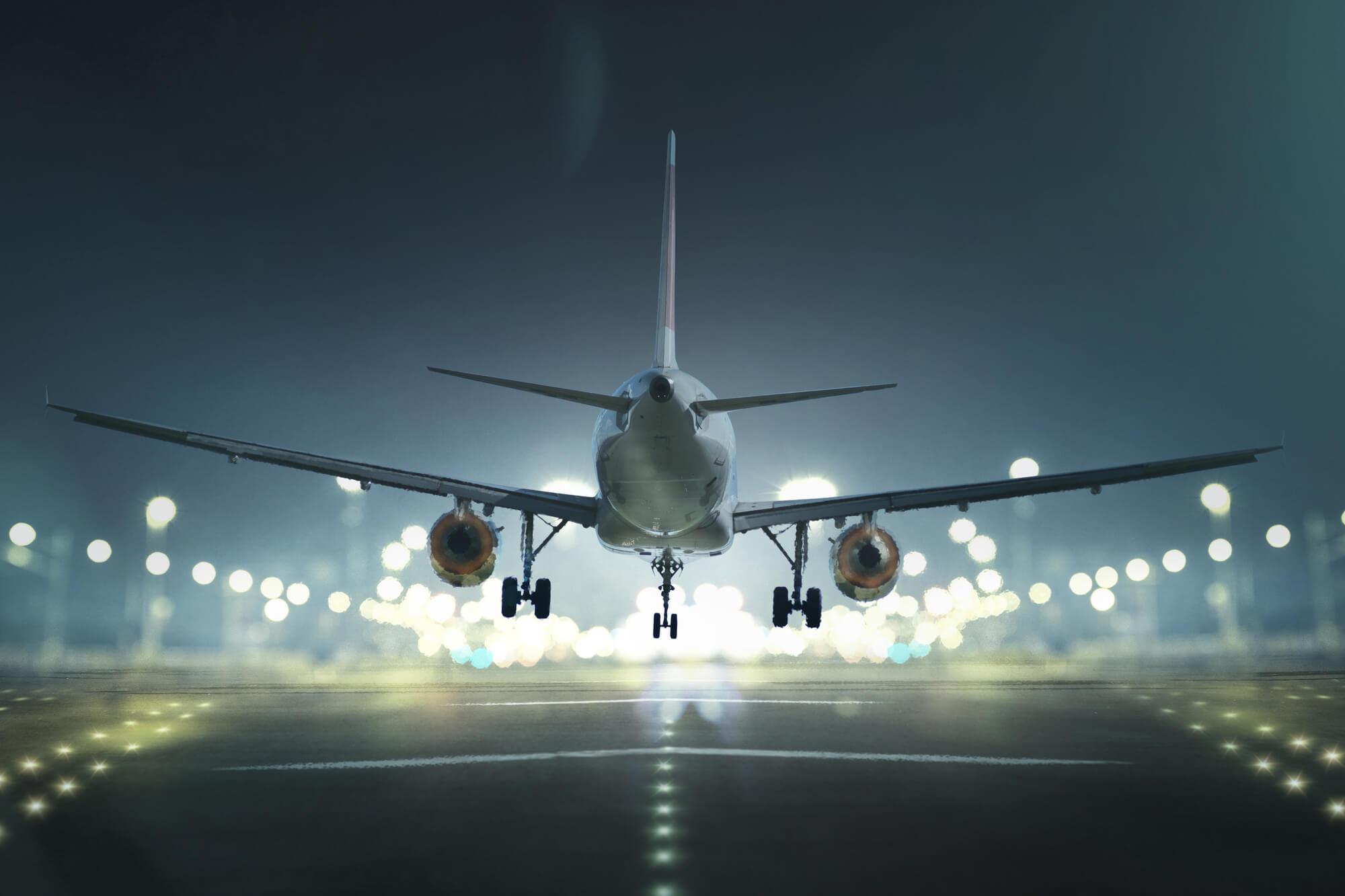 A plane landing on a lit runway at night