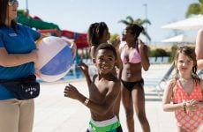 Encore Resort membership and family friendly activities. Children playing at a resort and a lifeguard holding an inflatable ball