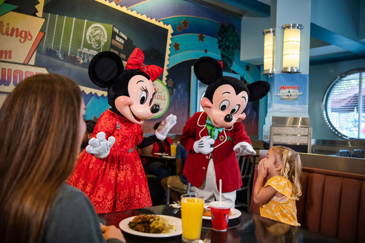Where to find characters at Disney World - a young girl excited to see Micjey and Minnie Mouse at her table in a restaurant