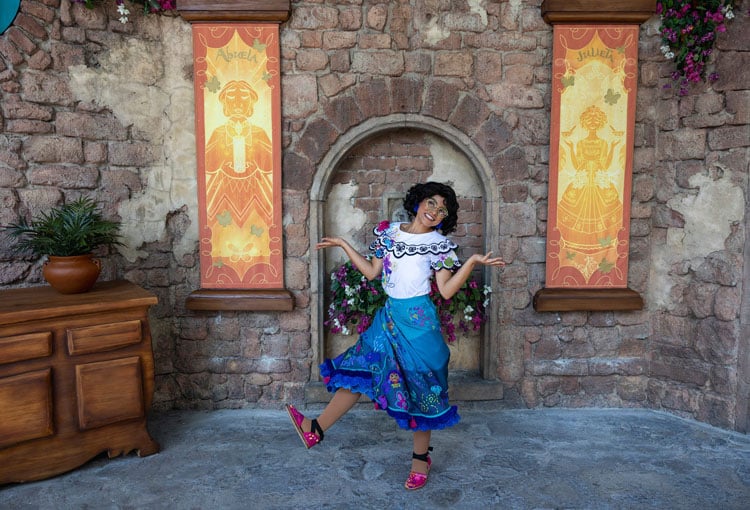 Where to find characters at Disney World - a person dressed as Mirabel from Encanto posing in front of a stone arched doorway