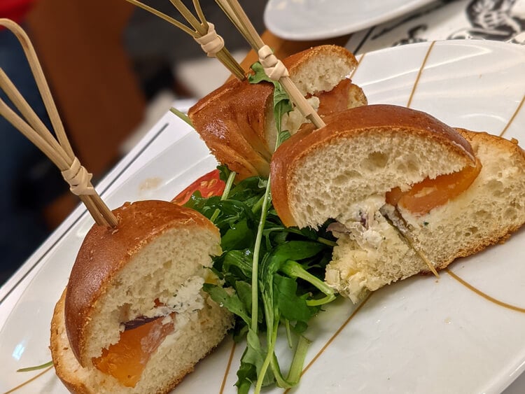 Mini salmon sandwiches and a salad of rocket and tomatoes on a white plate