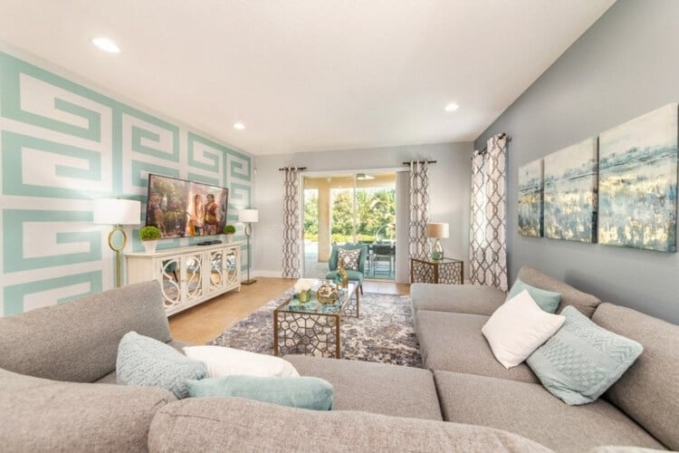 An Orlando vacation rental living room with soft mint green and beige colors, plush couches and a large television