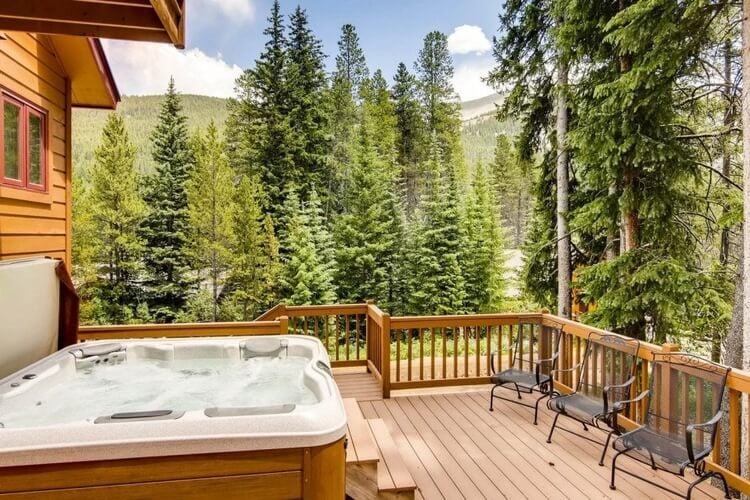 A wooden cabin the forest with a jacuzzi and decked area