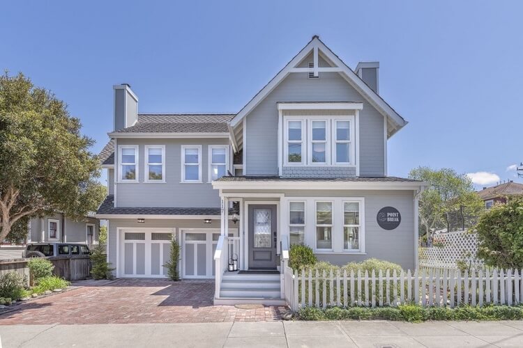 A pale blue wooden house with a white picket fence