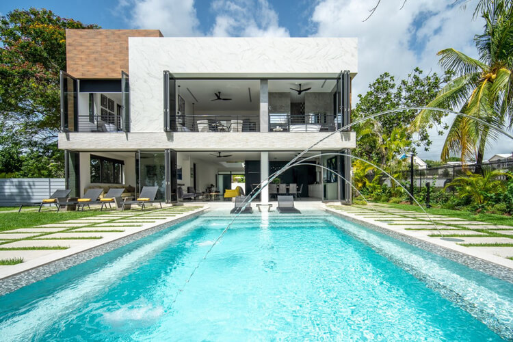 A two story luxury villa in Barbados with a private pool in the foreground.