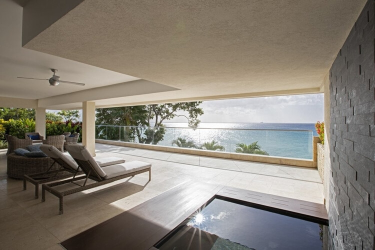 A seating lounge area with a balcony with a view of the Caribbean Sea.