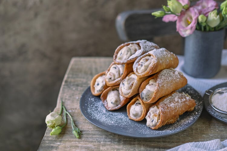 A plate piled high with cannoli, filled with cream
