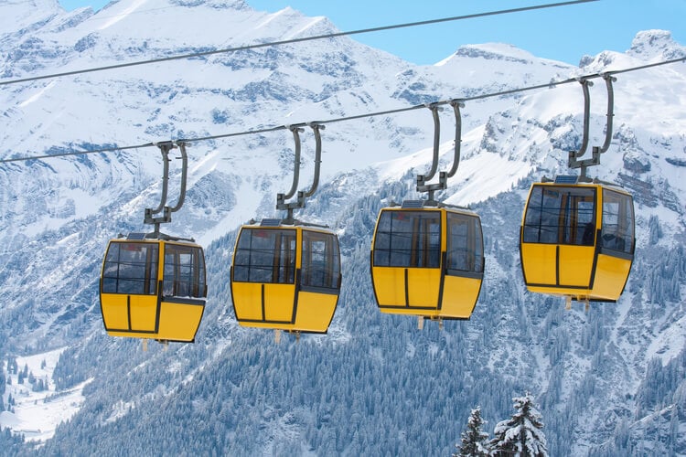 4 yellow gondolas against a snowy mountain backdrop